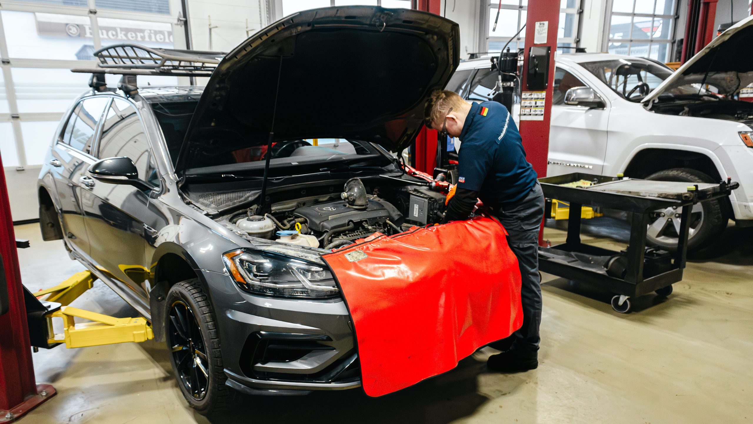 Motor Werke Red Seal Technician working on Volkswagen engine with red fender cover in Motor Werke workshop - VW repair & Diagnostics. 