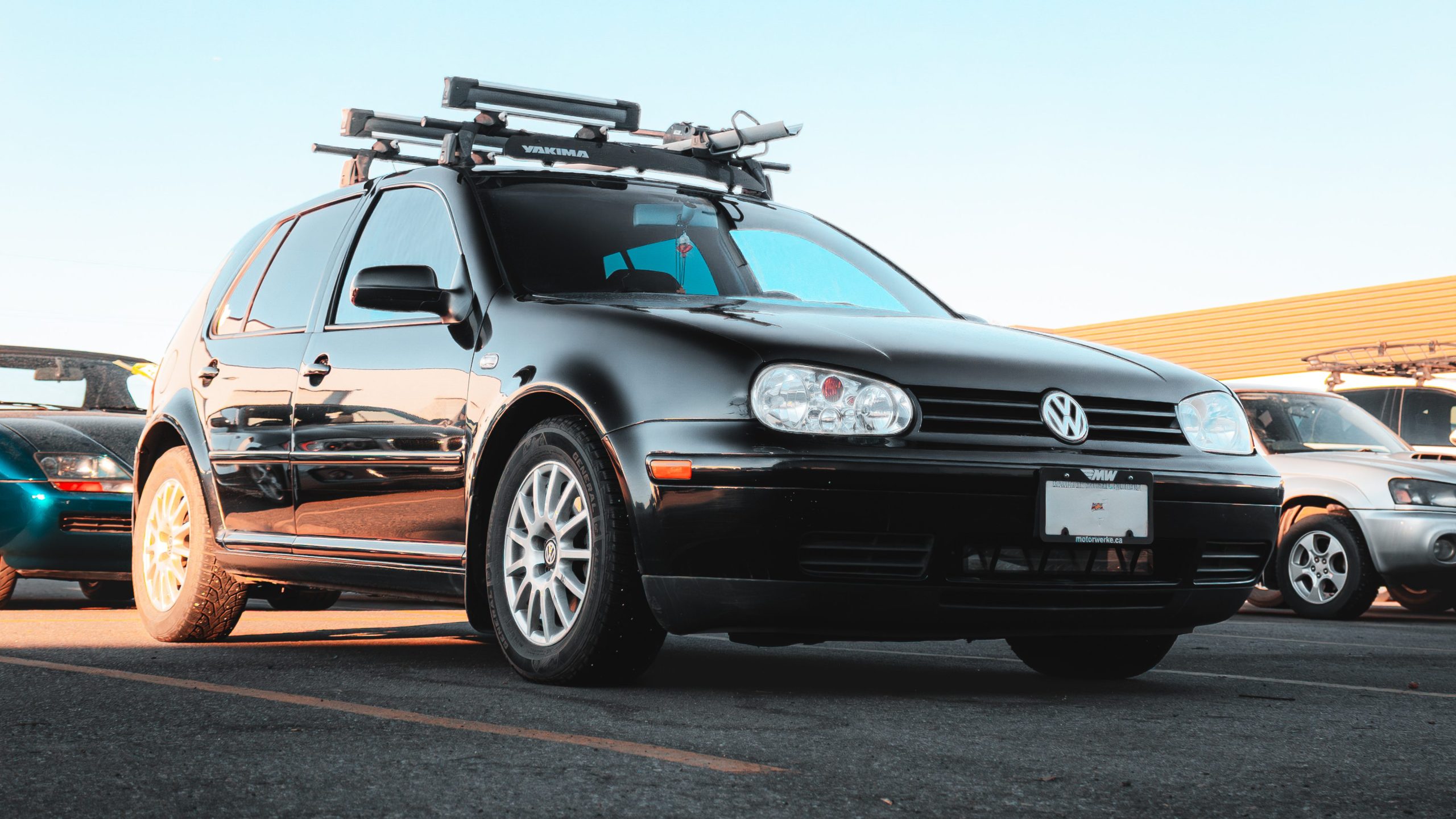 Low-angle shot of black Volkswagen Golf with roof rack in parking lot at Motor Werke - Kelowna VW Service and maintenance. 